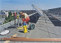 Ein Mann auf dem Dach eines Wohnhauses richtet ein Wärmesystem ein