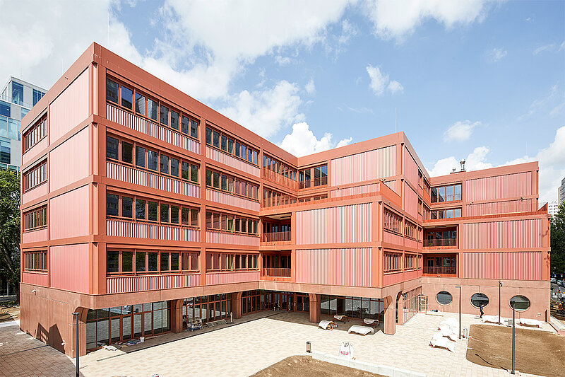 Seitliche Außenansicht des neu errichteten Heinrich-Hertz-Gymnasiums in Berlin-Friedrichshain, ein mehrgeschossiges Schulgebäude mit moderner Fassade.