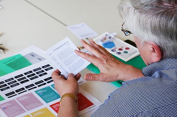 Eine ältere Frau liest etwas von einem Blatt Papier