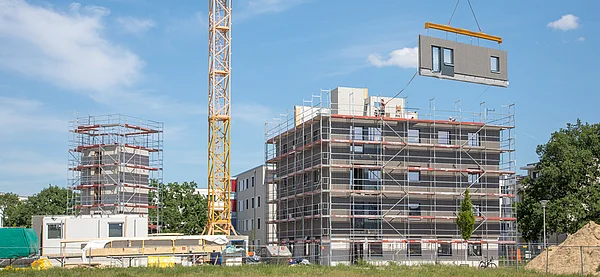 Ein Kran zieht eine Wand an einem Neubauprojekt hoch.