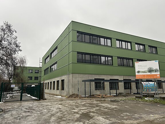 Blick auf die grüne Fassade und Bauschild