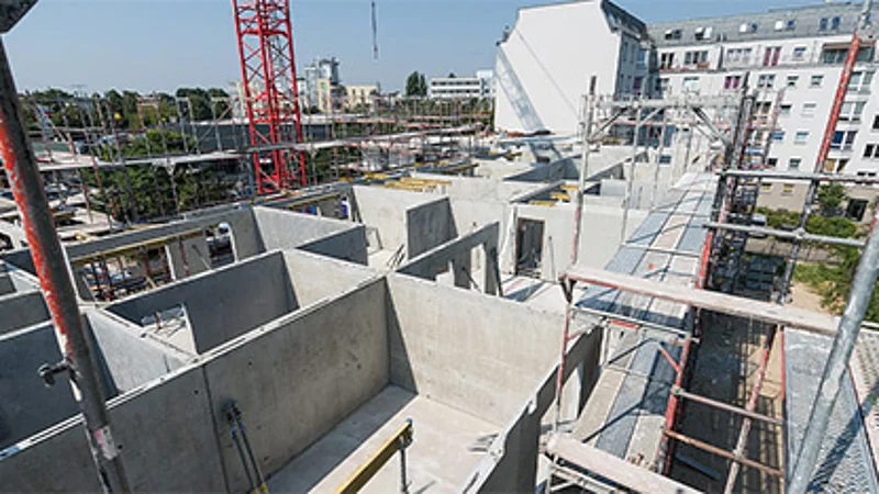 Foto eines Neubauprojektes von oben mit Einblick in den Rohbau und dem Grundriss der obersten Wohnung.