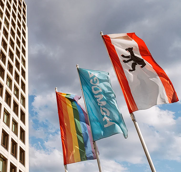 3 Fahnen vor einem Hochhaus: Berlin, HOWOGE, Regenbogen-Fahne