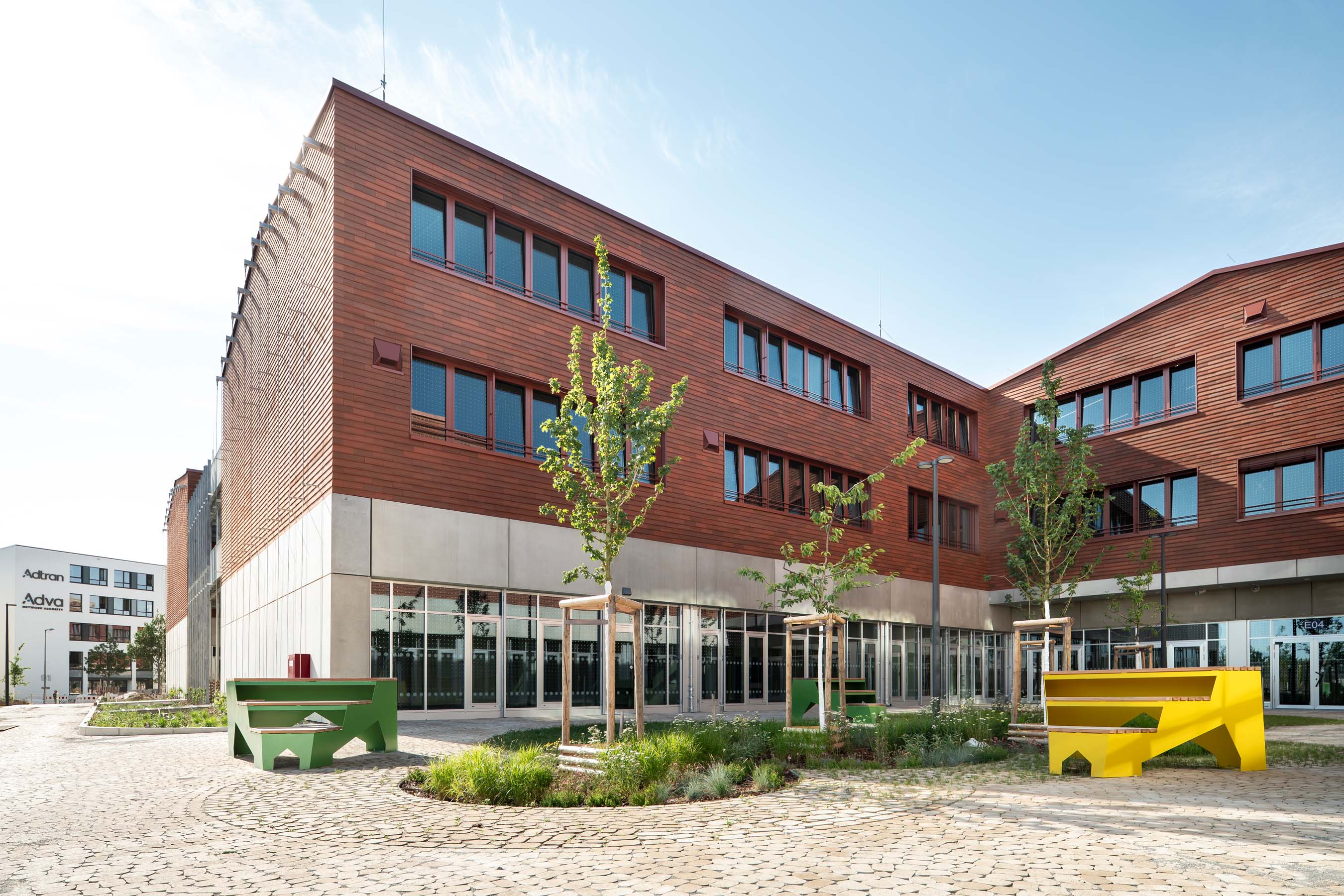 Außenansicht, Gebäude mit Holzfassade und Schulhof