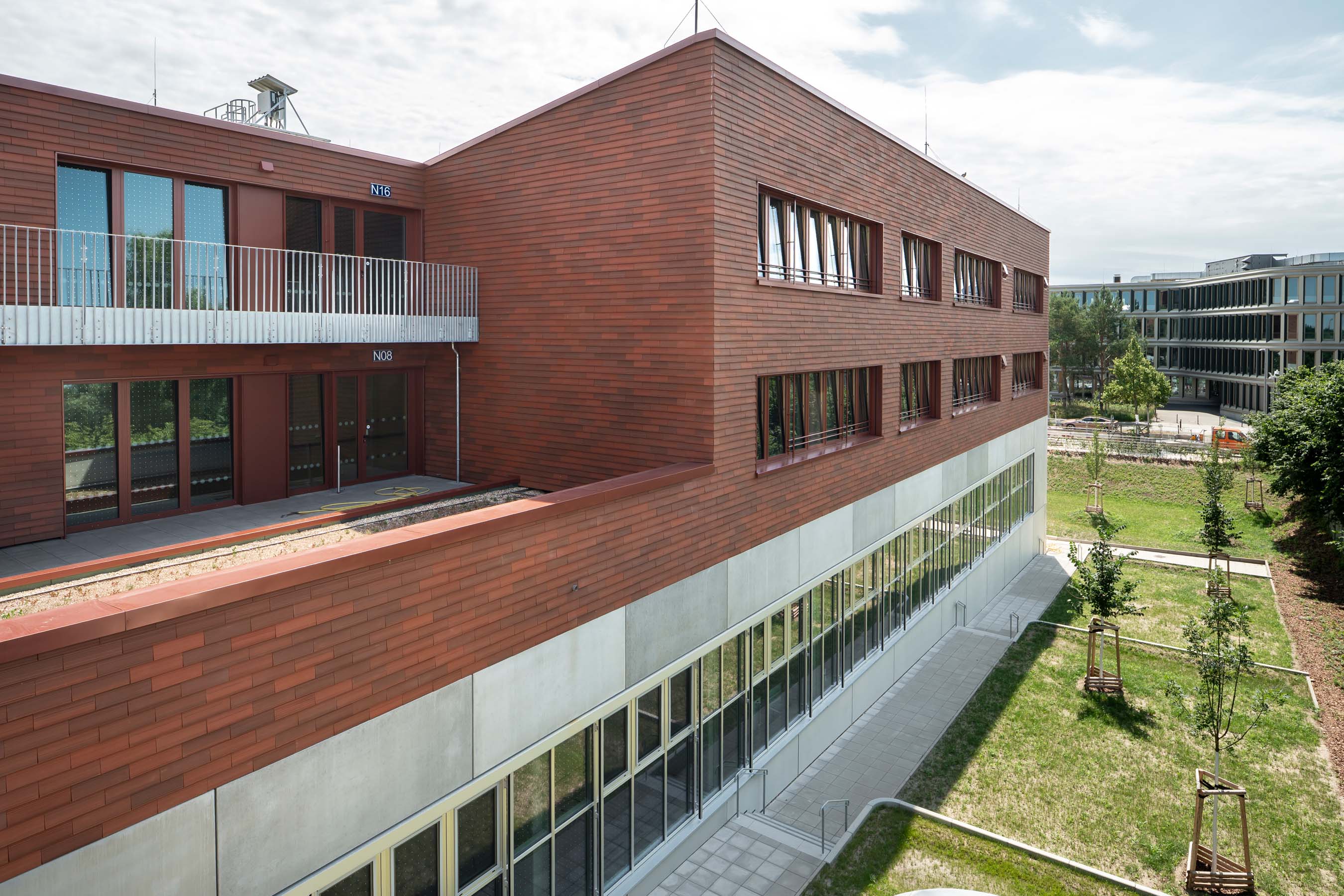 Außenansicht Gebäude mit Holzfassade und Schulhof