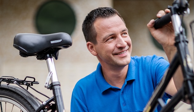 ein Mann im blauen Poloshirt an einem Fahrrad