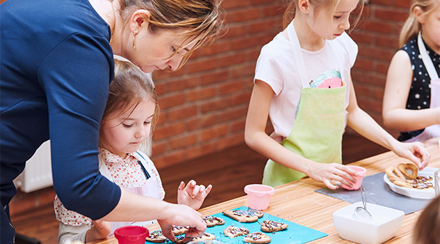 Erwachsene und Kinder backen zusammen.