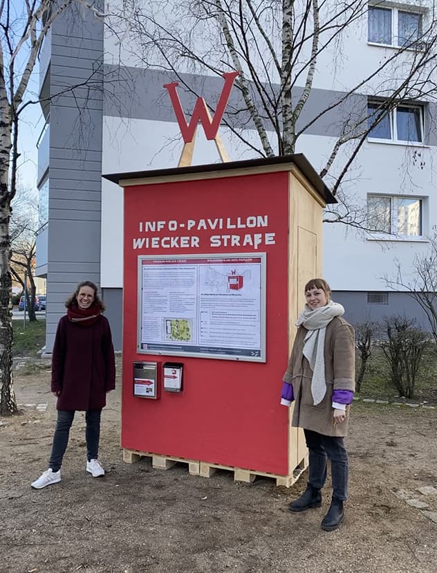 2 Frauen stehen vor einem Info-Pavillon zum Neubau Wiecker Straße